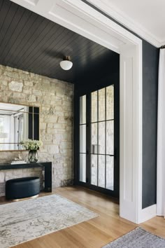 a living room with black and white walls, wood floors and a large mirror on the wall