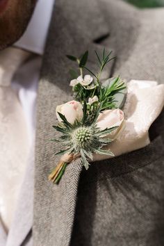 a boutonniere with white flowers and greenery is worn on a man's suit