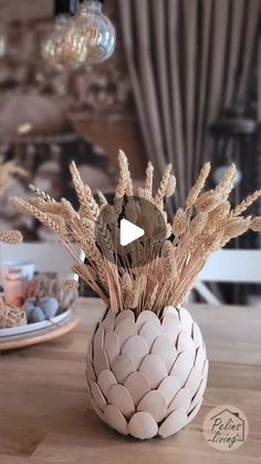 a vase filled with dried plants on top of a wooden table