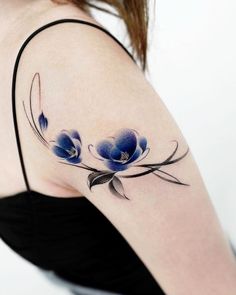 a woman's shoulder tattoo with blue flowers on the left side of her arm