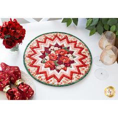 a table topped with a red and white quilted placemat next to two wine glasses