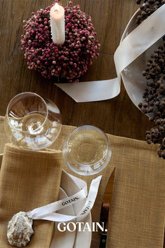 A Christmas table setting featuring mustard woven linen napkins, dried floral centerpieces with ribbon, and rustic decor on a wooden table.