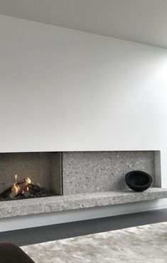 a modern fireplace in the middle of a living room with white walls and flooring