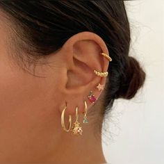 a close up of a person's ear with three different colored stones on it