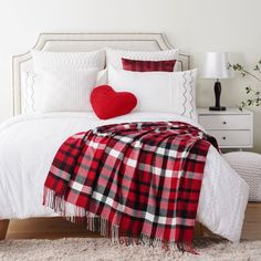 a red and white plaid blanket sitting on top of a bed next to a night stand