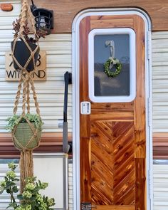 a wooden door with rope hanging from it and potted plants on the front porch