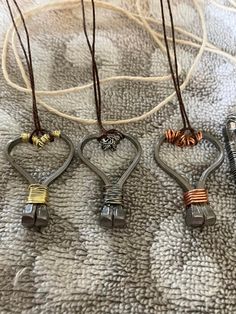 four heart shaped pendants are hanging on a white blanket with brown cords attached to them