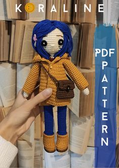 a crocheted doll with blue hair is being held in front of stacks of books