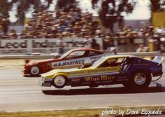 two race cars racing on a track with spectators in the background