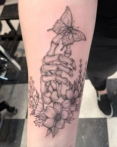 a woman's leg with flowers and a butterfly tattoo on the side of her arm