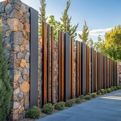 a stone and steel fence next to trees