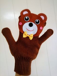 a brown teddy bear glove with a yellow bow tie on it's thumb and hand