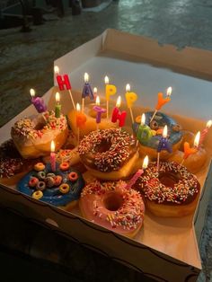 a box filled with lots of donuts covered in candles