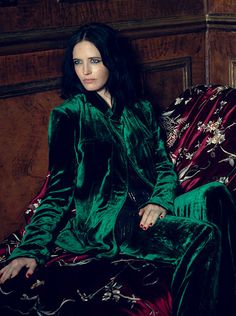 a woman sitting on top of a couch in a green velvet suit and matching pants