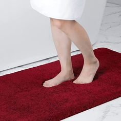 a woman standing on a red rug in the bathroom