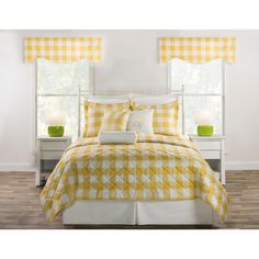 a bed with yellow and white checkered bedspread, pillows and two lamps