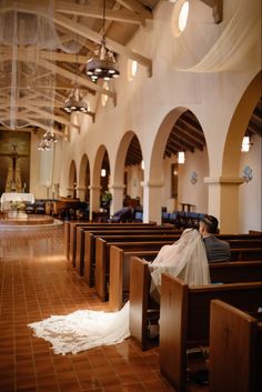 the bride and groom are sitting in the pews at the wedding ceremony, with their veil blowing in the wind