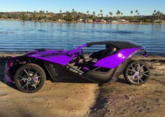 a purple and black sports car parked on the beach