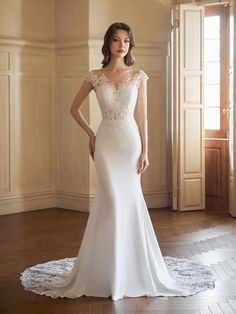 a woman in a white wedding dress standing on a wooden floor