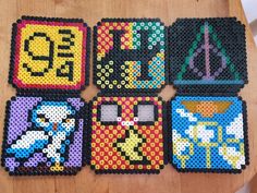 four coasters made out of perler beads are sitting on a wooden table top