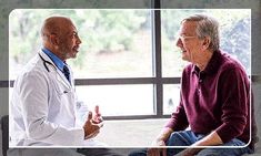 two men talking to each other in front of a window