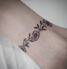 a woman's arm with flowers on it and leaves around the wrist tattoo design