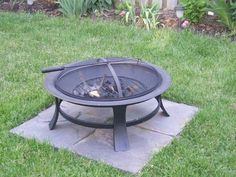 a fire pit sitting on top of a stone slab in the middle of a yard