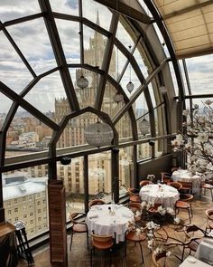 an indoor dining area with tables, chairs and large windows overlooking the cityscape