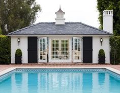 a pool house with black shutters and white trim