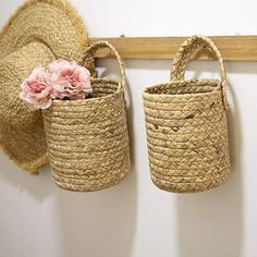 two baskets are hanging on the wall with flowers in them and one has a pink flower