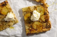 two slices of pizza with cheese and potatoes on top, sitting on wax paper next to each other