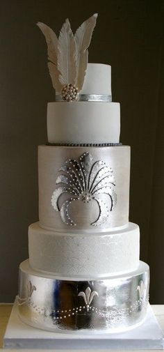 a three tiered wedding cake with white frosting and silver decorations on the top