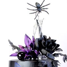 a black cake with purple flowers and spider decorations