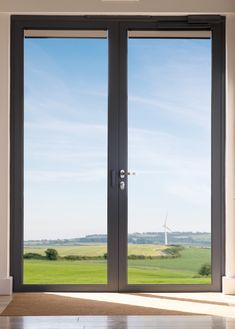 an open door leading to a field with windmills in the distance