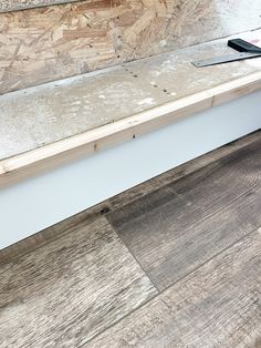 a wooden bench sitting on top of a hard wood floor next to a building under construction