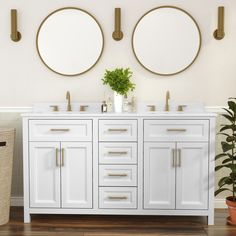 two round mirrors are above the double sink vanity in this white bathroom with wood flooring