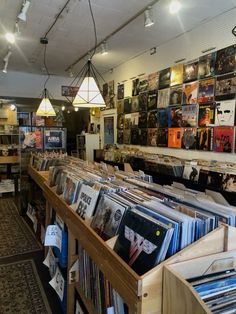 the inside of a record store with many records on shelves and lights hanging from the ceiling