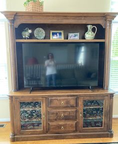 a woman is standing in front of a large entertainment center that has drawers and doors