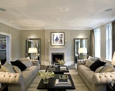 a living room filled with furniture and a fire place in front of a mirror on the wall