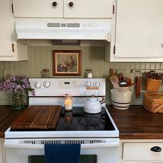 a white stove top oven sitting inside of a kitchen next to a wooden countertop