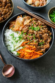 a bowl filled with meat and vegetables next to chopsticks on a table top