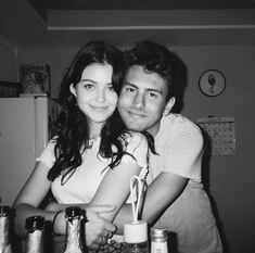 black and white photo of man and woman hugging each other in front of the refrigerator