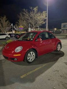 a red car parked in a parking lot at night