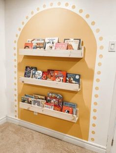 three wooden shelves with books on them against a yellow and white wall in a children's room