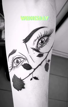 a woman's leg with an eye and leaves on it that says wednesday written in green