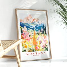 a chair next to a poster on the wall with mountains and flowers in front of it