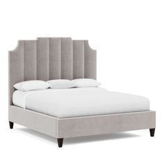 an upholstered bed with white sheets and pillows