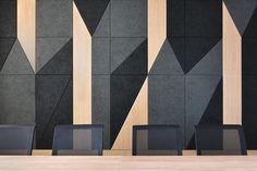 three black chairs sitting in front of a wall with geometric designs on it's sides