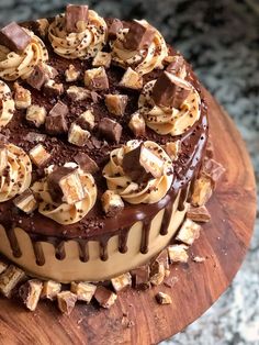 a cake with chocolate and nuts on top sitting on a wooden board next to a granite counter