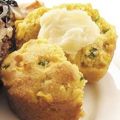 three muffins on a white plate topped with butter and other food items next to each other